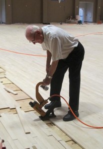 Retired Christian Brother, Alfred Baltz, a longtime resident and former faculty member and athletic director for SPS, nails floorboards in place on the new basketball court. Bro. Alfred was instrumental in building many campus structures including the old gym and Horack and Booth Pavilions. (photo by Karen Hebert)