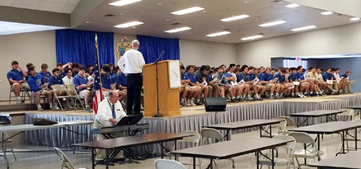 Brother Ray leads the seniors in practice for graduation, while Brother Ken accompanies on the piano