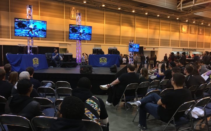 A group of attendees spectates a Street Fighter V tournament.